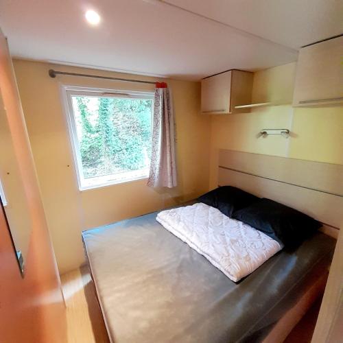 une petite pièce avec un lit et une fenêtre dans l'établissement Camping Margot, à Archiac