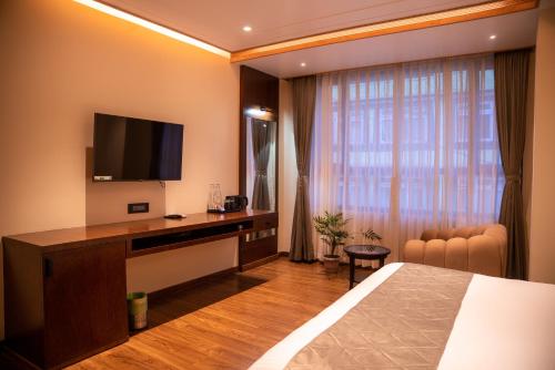 a hotel room with a bed and a desk with a television at Evara Hills, Gangtok in Gangtok