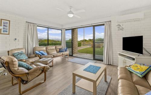 a living room with couches and a flat screen tv at Sun & Surf Aldinga Beach Apartment in Aldinga Beach