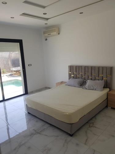 een groot bed in een witte kamer met een raam bij Villa Kenza in Douar el Khima