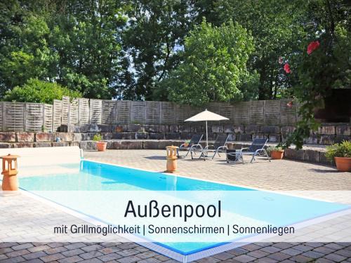 a swimming pool with chairs and an umbrella at Gut Weihersmühle in Leutershausen