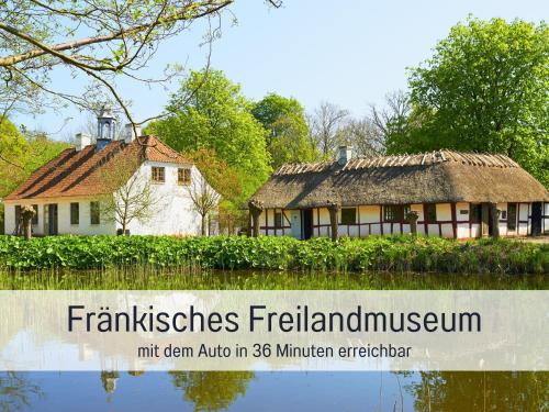 an old house with a thatched roof next to a river at Gut Weihersmühle in Leutershausen