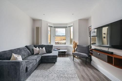 a living room with a couch and a flat screen tv at Stunning spacious Duplex with garden 141a in Hastings
