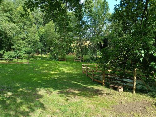 a wooden fence in a field with trees and grass at Le Reflet du Trèfle in Puybegon