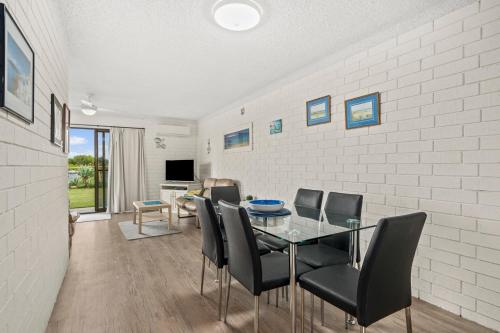 a dining room with a glass table and chairs at Sun & Surf Aldinga Beach Apartment in Aldinga Beach