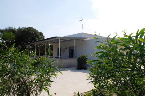 a white house with a patio in front of it at Villa Il Giardino con Piscina a soli 350 mt dalla Spiaggia di Punta Prosciutto in Punta Prosciutto