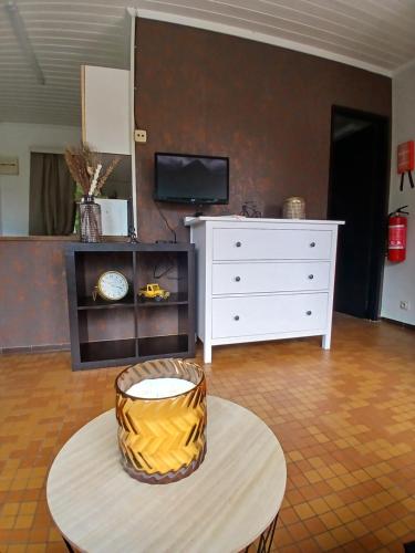 Una sala de estar con una cómoda blanca y una mesa. en L'Oxymore, en Hastière-par-delà