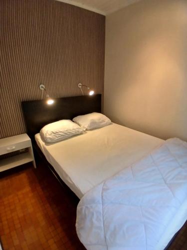 Un dormitorio con una gran cama blanca con dos almohadas. en L'Oxymore, en Hastière-par-delà