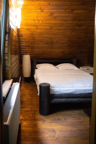a bedroom with a bed in a wooden wall at Pensiunea Lac in Arefu