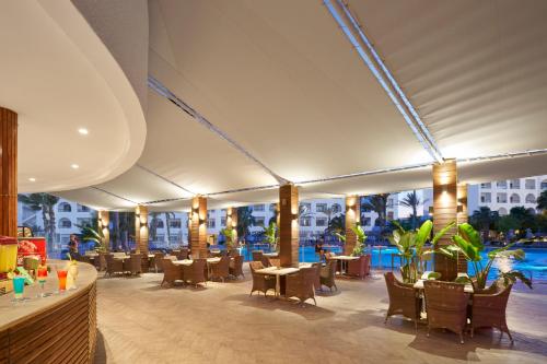 a restaurant with tables and chairs and a pool at Nozha Beach Resort & Spa in Hammamet