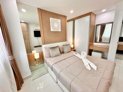 a bedroom with a bed with a white ribbon on it at PALMTREE BREEZE Condo in Amazon Residence in Jomtien Beach