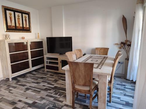 a dining room with a table and chairs and a television at SalinaSOL in Roquetas de Mar