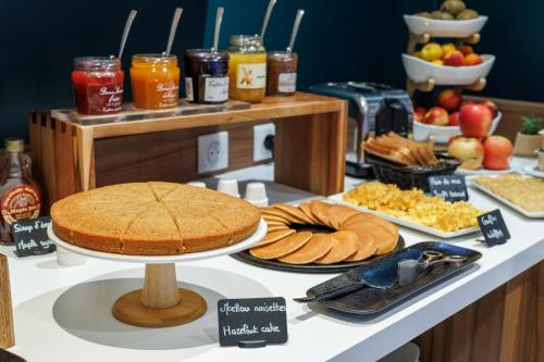 a table with a cake and other food on it at The Originals Boutique, Hôtel Le Pariou, Issoire in Issoire