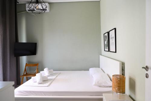 a bedroom with a bed with white sheets and a chair at Hygge Home at Trikala in Tríkala