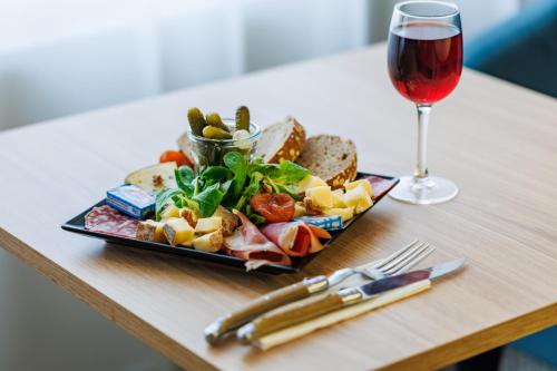 a plate of food and a glass of wine on a table at The Originals Boutique, Hôtel Le Pariou, Issoire in Issoire