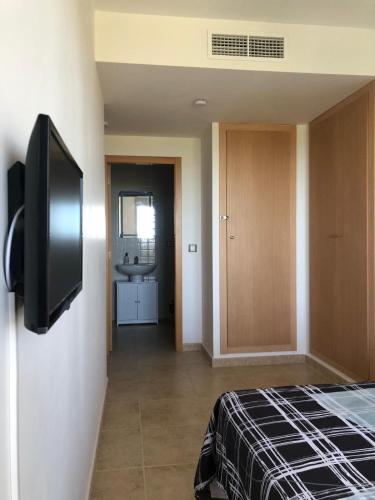 a room with a bed and a flat screen tv at Apartamento con vista al mar in Sant Jordi