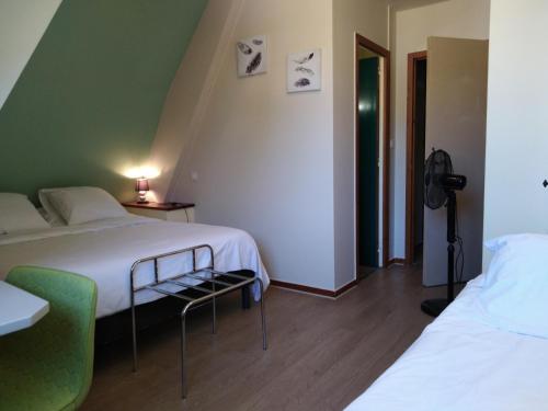 a bedroom with two beds and a green wall at Hôtel du Pont et Restaurant à Groléjac in Groléjac