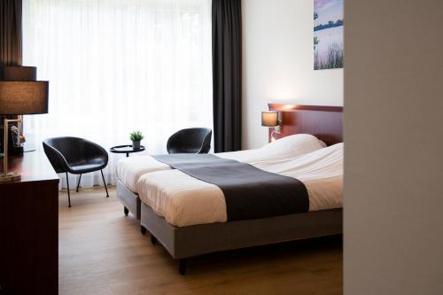 a hotel room with a bed and two chairs at Hotel Umberto in Wijchen