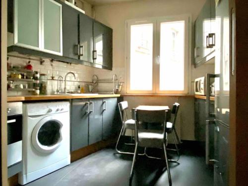 une cuisine avec un lave-linge, une table et des chaises dans l'établissement Appartement de charme près Montmartre, à Paris