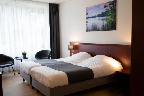 a hotel room with a bed and a window at Hotel Umberto in Wijchen