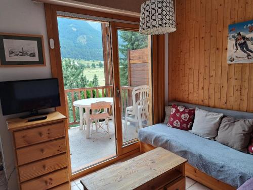 Il comprend un salon avec un canapé, une télévision et un balcon. dans l'établissement Marmotte Le Monêtier Apartment, au Monêtier-les-Bains