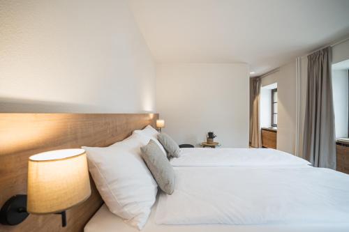 a bedroom with a bed with white sheets and pillows at Hotel Brocco & Posta in San Bernardino