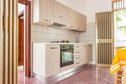 a kitchen with white cabinets and a stove top oven at Villa Kareema 2D con accesso diretto alla Spiaggia di San Pietro in Bevagna in San Pietro in Bevagna