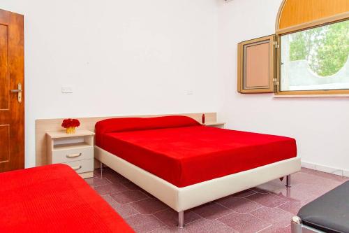 a bedroom with a red bed and a window at Villa Kareema 2D con accesso diretto alla Spiaggia di San Pietro in Bevagna in San Pietro in Bevagna