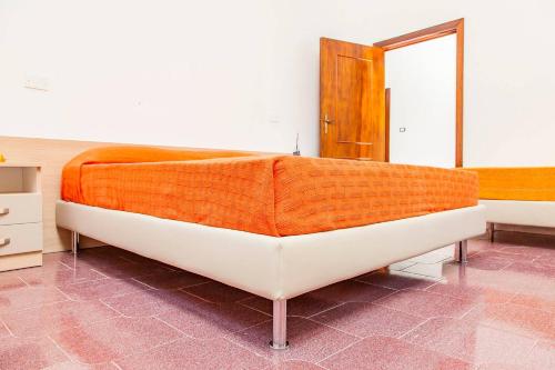 a bed with an orange blanket on it in a room at Villa Kareema 2D con accesso diretto alla Spiaggia di San Pietro in Bevagna in San Pietro in Bevagna