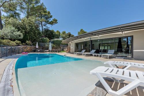 - une piscine avec 2 chaises blanches à côté d'une maison dans l'établissement Superbe et spacieuse propriété avec piscine et spa, à Saint-Gély-du-Fesc