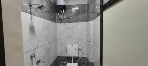 ein Badezimmer mit Toilette mit Marmorwänden und Dusche in der Unterkunft TARA Guest House in Ujjain