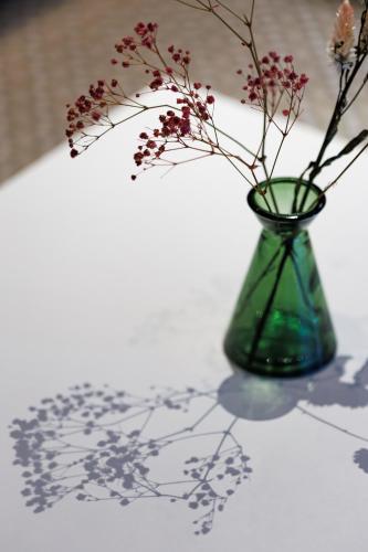 a green vase with flowers in it on a table at The Originals Boutique, Hôtel Le Pariou, Issoire in Issoire