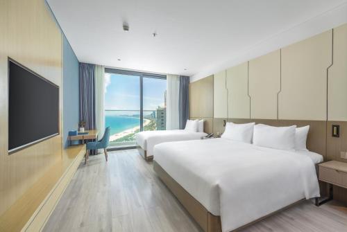 a hotel room with two beds and a television at Awaken Da Nang Hotel in Da Nang