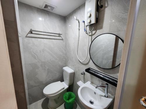 a bathroom with a toilet and a sink and a mirror at Stone House Hotel Manila in Manila
