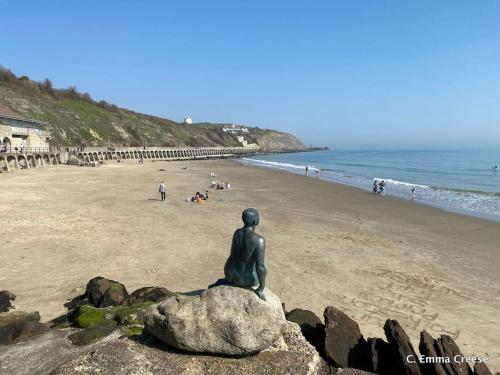 a statue sitting on a rock on a beach at Little Sycamore in Lyminge