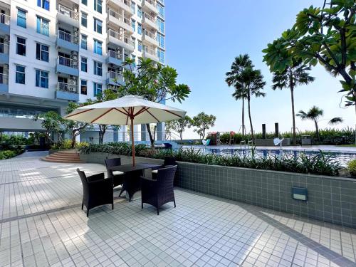 a table and chairs with an umbrella next to a building at Benson Tower Surabaya Apartment 2BR by Le Ciel Hospitality in Lontar
