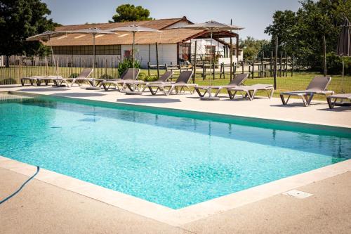a swimming pool with chaises and chairs in a yard at Lou Mas Dou Juge in Saintes-Maries-de-la-Mer