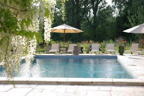 a swimming pool with chairs and umbrellas at Bastide Rose in Le Thor