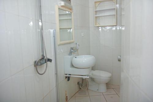 a white bathroom with a toilet and a sink at studio avec piscine a 1 minutes de la mer in Sali Nianiaral