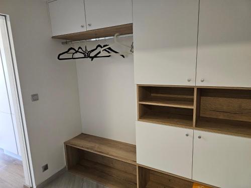 einen Schrank mit weißen Schränken und Holzregalen in der Unterkunft NEW Apartment - O2 Arena Prague with parking in Prag