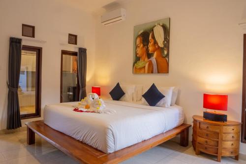 Un dormitorio con una cama blanca y un cuadro en la pared. en VIlla Dafne, en Seminyak