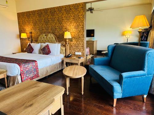 a hotel room with a bed and a blue chair at Indana Palace Jaipur in Jaipur