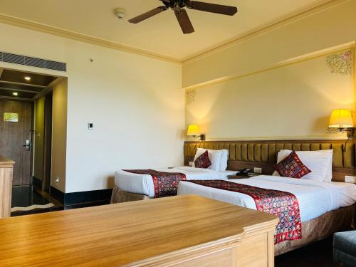 a hotel room with two beds and a table at Indana Palace Jaipur in Jaipur