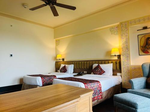 a hotel room with two beds and a chair at Indana Palace Jaipur in Jaipur