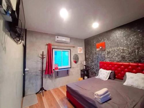 a bedroom with a red bed and a window at แม่ให้ โฮมสเตย์ in Ban Tha Rawaek (1)