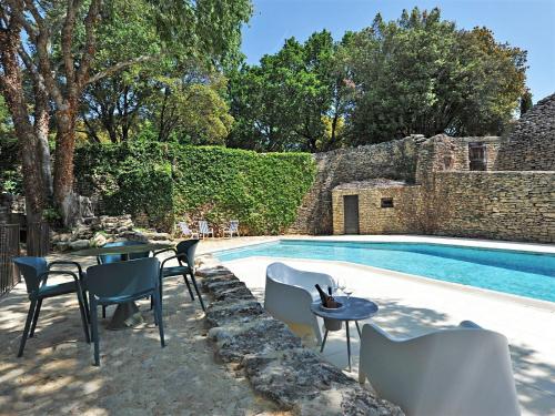 - une piscine avec des chaises et une table à côté d'un bâtiment dans l'établissement Le Chant des Bories, à Gordes