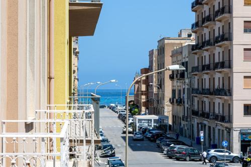 a city street with parked cars and the ocean at B&B Il Sole Blu in Trapani