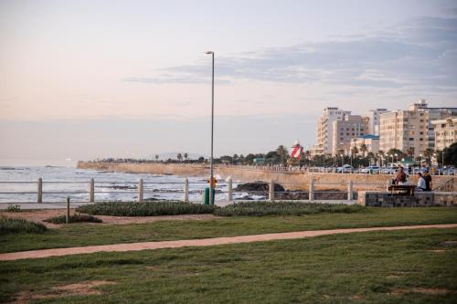 people sitting on a bench next to the beach at Seaside 9 l Stylish Aparthotel in Three Anchor Bay in Cape Town