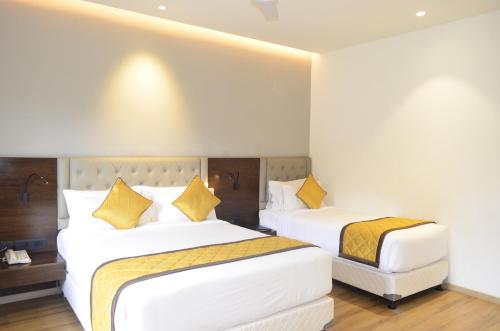 a hotel room with two beds with yellow pillows at The Aurum Subrahmanya in Subrahmanya