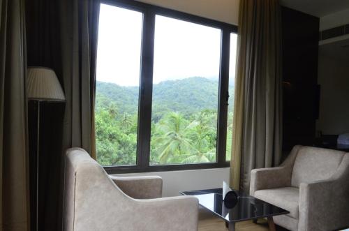 a living room with two chairs and a large window at The Aurum Subrahmanya in Subrahmanya